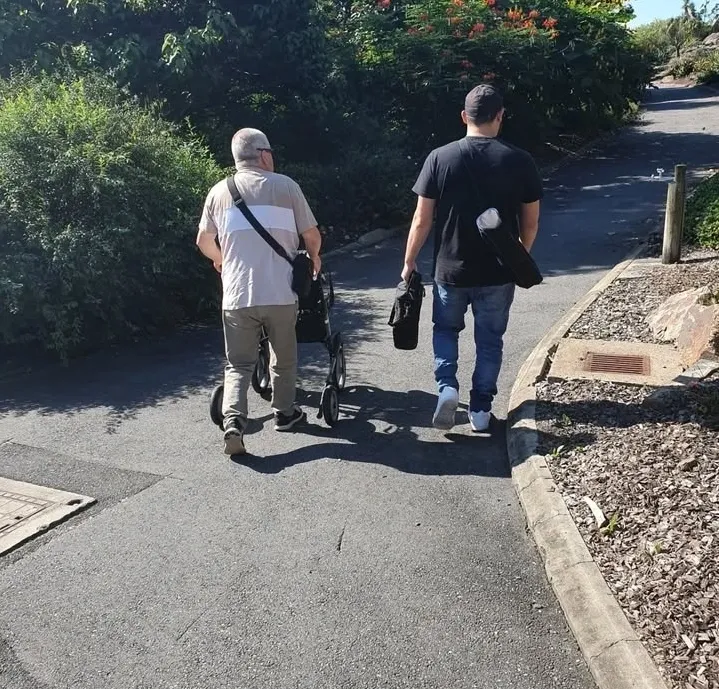 A support worker walking beside a participant using a walking frame