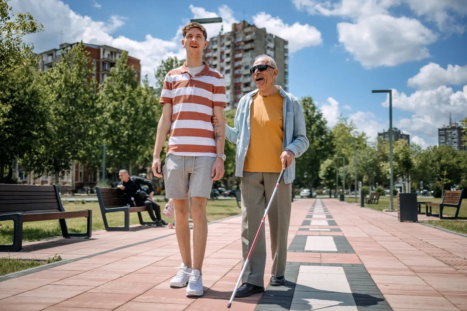 A support worker walking with a person using a white cane