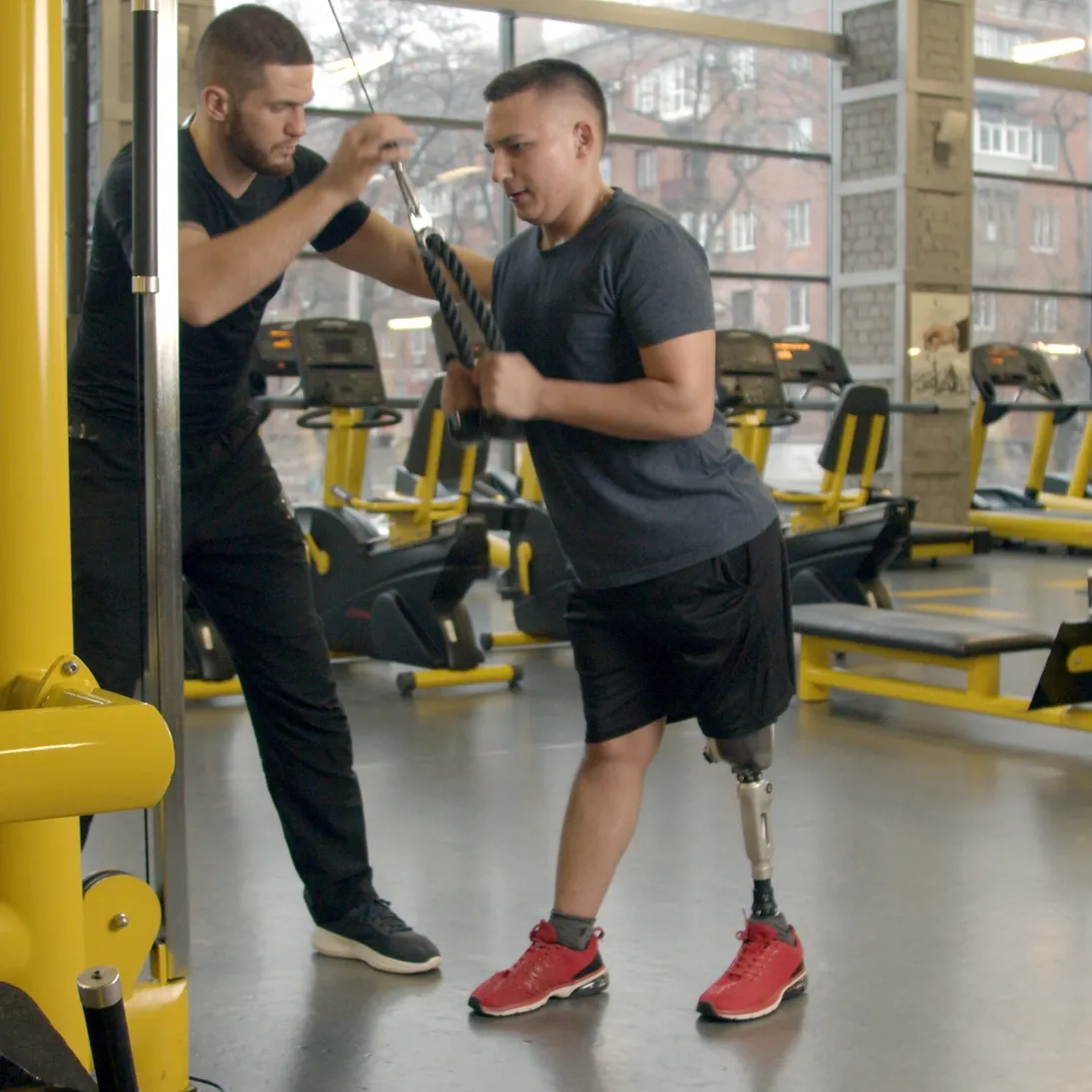 A trainer supporting a person during a gym exercise
